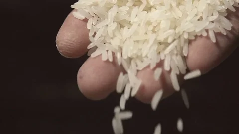 Slow motion raw rice grains falling from man's hand Video stock 79617521