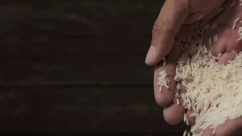 Slow motion raw rice grains falling from man's hand Video stock 79617817