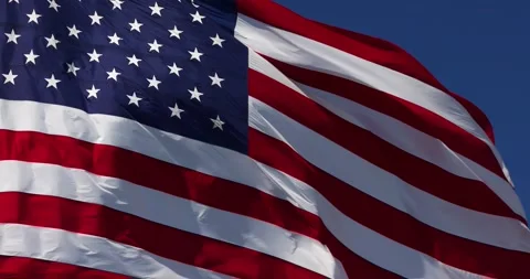 Slow Motion Real American Flag Waving In Wind Against a Deep Blue Sky Stock Footage 156267626