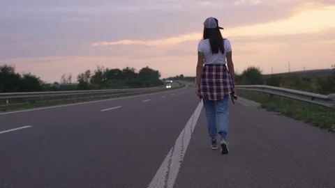 Slow-motion rear view hipster woman tourist walking forward highway countryside Stock Footage 110816296