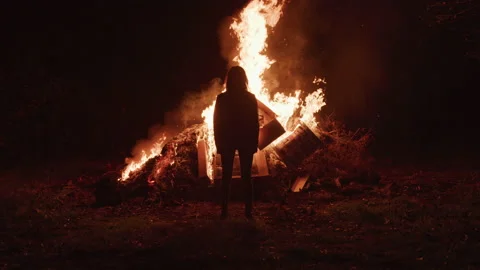 Slow motion rear view shot of woman standing in front of huge burning pile Stock Footage 208776082