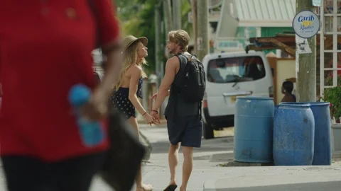 Slow motion rear view view of tourist couple walking and kissing in street / Stock Footage 114768285