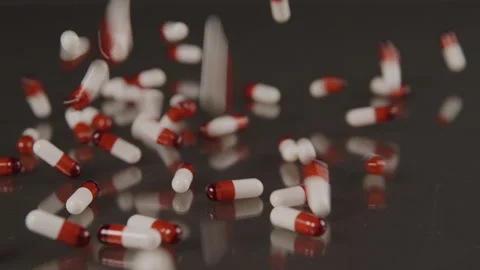 Slow motion of red and white pill capsules falling onto black background Stock Footage 208759428