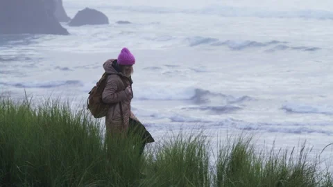 Slow motion RED camera shot with woman at scenic rocks in stormy ocean shore 6K 스톡 동영상 168146400