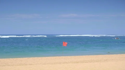 Slow motion of a red flag is swaying in wind on a tropical sandy beach Video stock 114821550