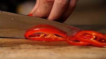 Slow motion - red pepper being sliced into pieces with sharp knife by chef  Stock Footage 85766138