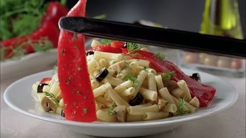 Slow motion red pepper is being placed over the pasta on the serving plate. Stock Footage 140672211