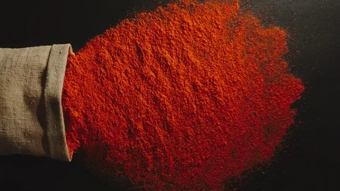 SLOW MOTION: Red pepper powder pours out of falling bag - Top view Stock Footage 98666245