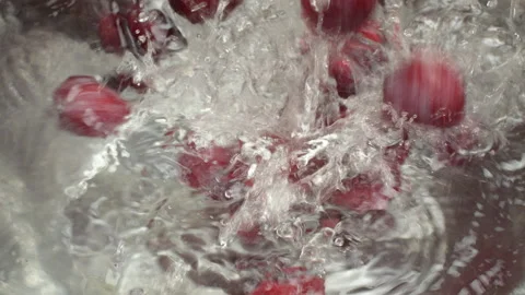 Slow Motion Red Plums Splashing into Water Bowl Top View Stock Footage 319916678