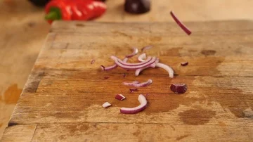 Slow motion - Red sliced onions being dropped onto chopping board in kitchen  Stock Footage 85764358