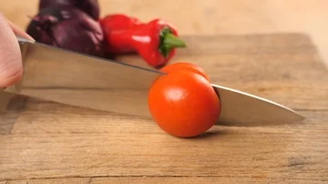 Slow motion - red tomato being chopped in half with sharp knife  Stock Footage 85766739