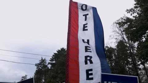 Slow motion of a red white and blue vote here sign blowing in the wind Stock Footage 97473768