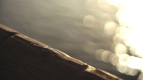 Slow motion reflection of sun in the water. Wooden railing in the foreground. 库存影片 88429181