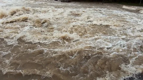 Slow motion right pan close up wide raging flooded river after season rain Stock Footage 121929531