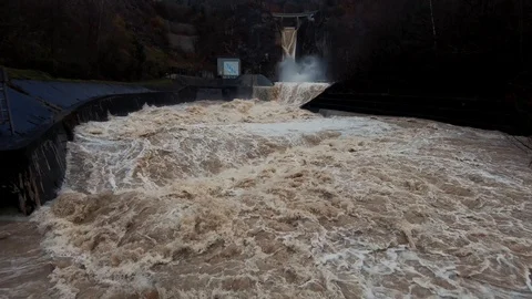 Slow motion right pan wide shot dirty turbulent flood water leaving dam Stock Footage 122205190