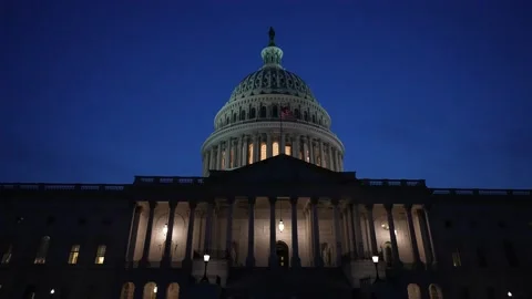 Slow motion to right showing the US Capitol with lights and flags waving in Stock Footage 239695110
