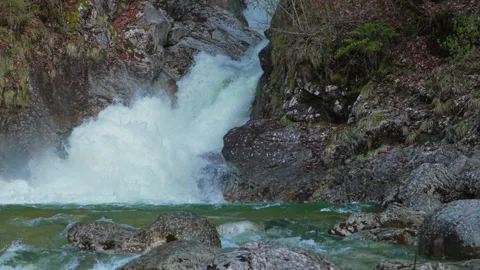 Slow motion of Rindbach Waterfall rushing into clear mountain river in Ebensee Stockbeeldmateriaal 345683450