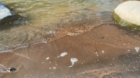 Slow motion ripples of river water surface on sandy and rocky river banks Video stock 320977144