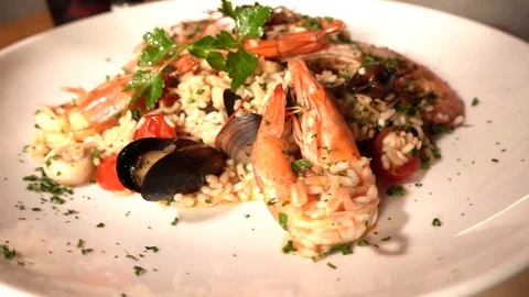 Slow-motion of risotto with jumbo shrimp rotation on a white plate Stock Footage 129928021