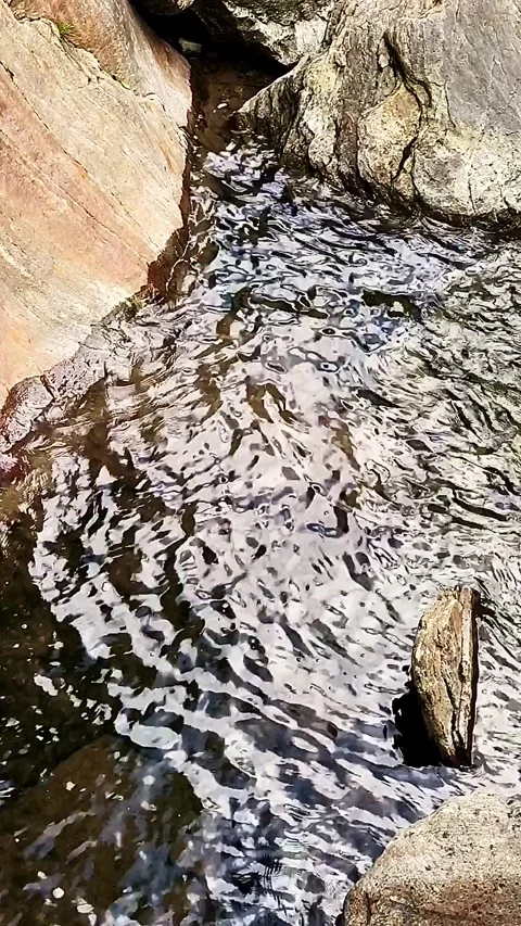 Slow-motion river pool from above with red textured rock in the corners Stock Footage 248377757