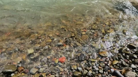 Slow motion of river waves crashing against pebbles on the river bank Stock Footage 320984896