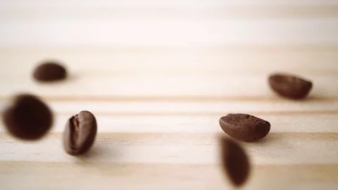 Slow motion of roasted coffee bean drop on light brown wooden texture Stock Footage 111502499