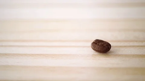 Slow motion of roasted coffee bean drop on light brown wooden texture Stock Footage 111502564