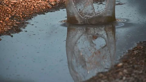 Slow motion rock throwing in a small puddle on countryside road Stock Footage 135605945