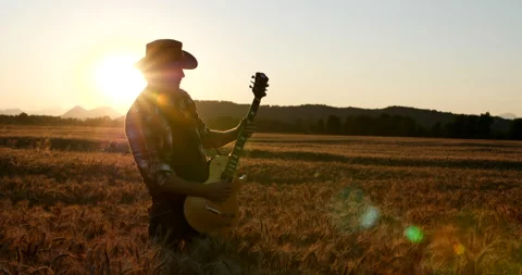 SLOW MOTION: Rocker playing electric guitar on a wheat field in sunset Stock Footage