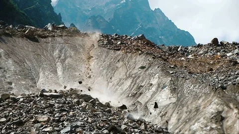 Slow motion rockfall in the mountains close up. People run away from falling Stock Footage 93873132