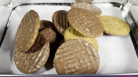 Slow motion of rolled oats and chocolate coated biscuits pouring into a tin. Stock Footage 300278932