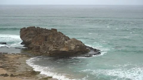 Slow motion of rolling waves crashing on a big beach boulder Stock Footage 301510067
