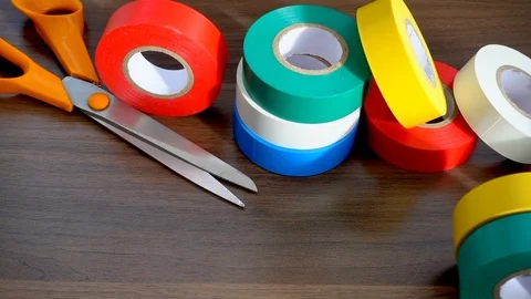 Slow motion: Rolls of red, yellow, green, blue and white electrical tape. Video stock 97169799