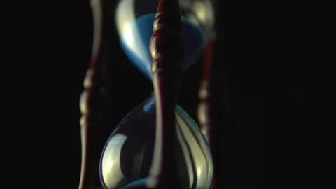 Slow motion rotation of sand timer clock with sand flowing from through hour  Stock Footage 117883852