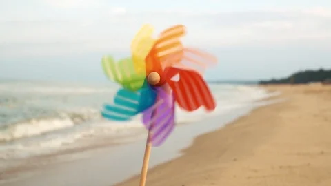 A slow motion round colored plastic windmill wind stands in the sand by the sea Video stock 96391161