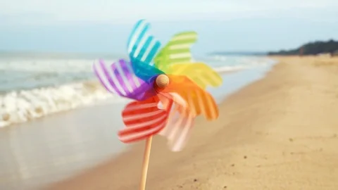A slow motion round plastic windmill with blowing wind stands in the sand Stock Footage 96391255