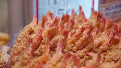 Slow-motion rows of crisp shrimp tempura with upright orange tails Video stock 347681026