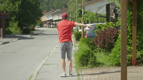 SLOW MOTION Rude courier making his round around the suburbs kicks three parcels Stock Footage 140044672