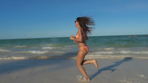 SLOW MOTION Running athletic thin girl in shallow water 動画素材 86994540