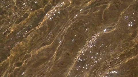 Slow motion of running water over sand beach with flecks of sunlight Видео 75896178