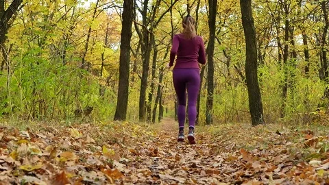 Slow motion Running - woman runner jogging on autumn forest path. Fit female Stock Footage 81673776