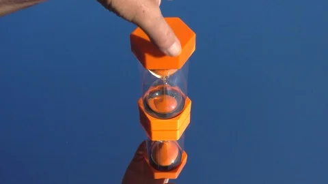 Slow motion: Sand timer placed onto a blue mirrored surface. Video stock 91919315