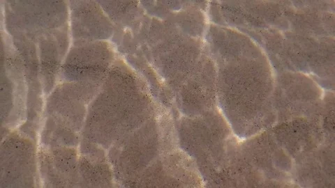 Slow motion of sandy bottom surface from underwater with sun rays reflection. Vídeos de archivo 72107913