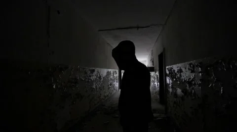 Slow motion of a scary guy with hood in an abandoned building backlight Stock Footage 58613636