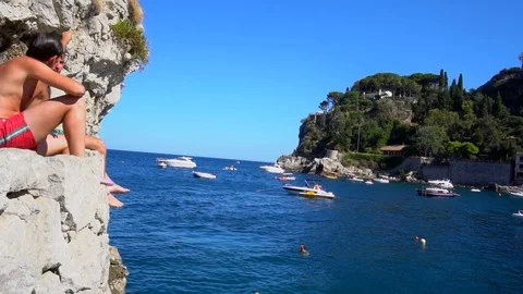 Slow motion scene of a boy diving from a rock in the blue sea. Stock Footage 91688148