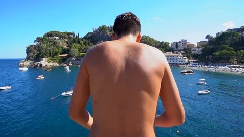Slow motion scene of a boy diving from a rock in the blue sea. Stock Footage 91688256