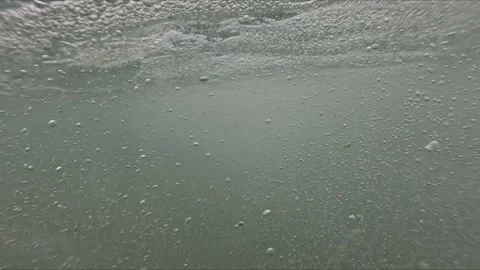 Slow motion scene of camera entering sea showing air bubbles and soft waves.. Video stock 315526207