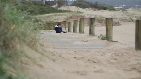 Slow motion scene of child at beach sitting at pathway and playing with sand 스톡 동영상 125983834