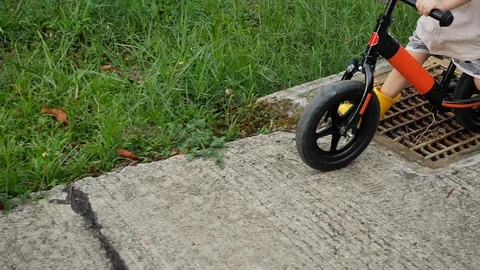 Slow motion scene, cute boy playing balance bike on street with the rainy day Stock Footage 113403234