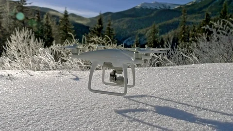Slow motion scene of a drone hanging in the air just above the snowy ground in Video stock 97971045